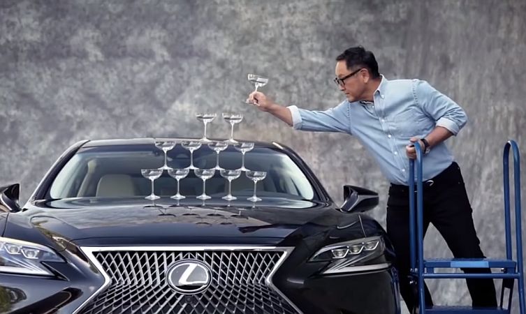 Toyota Motor Corporation CEO Akio Toyoda stacks champagne glasses on the bonnet of a Lexus LS derivative.