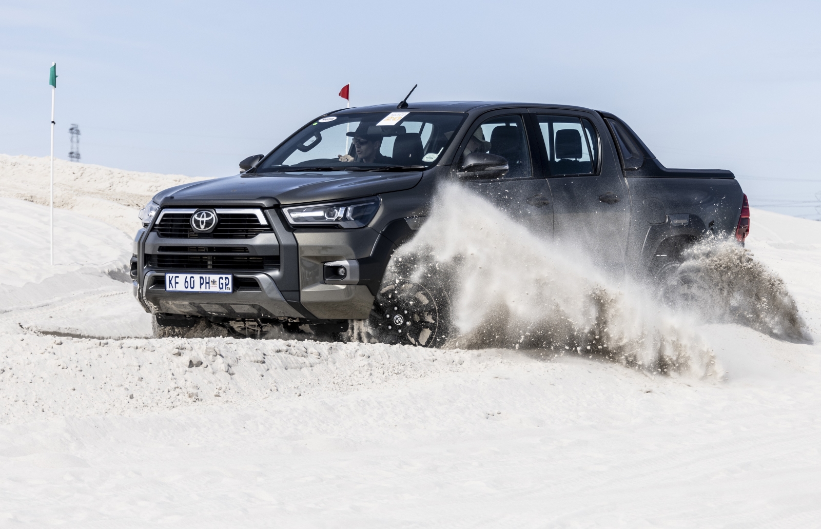 Toyota Hilux double-cab 4x4 on a sand dune.