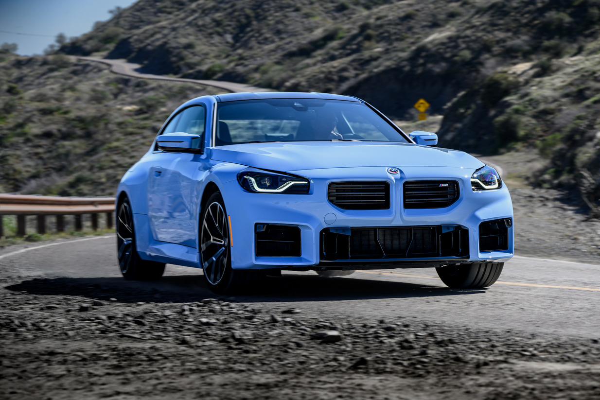 2023 BMW M2 coupe, driving on a mountain pass, front three-quarter view.