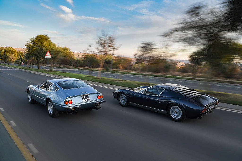 Ferrari Daytona (left) flanked by a Lamborghini Miura, rear three-quarter tracking shot